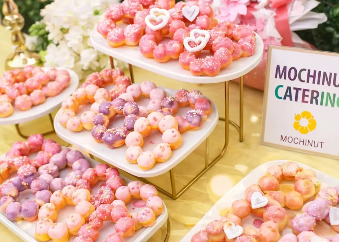 A Mochinut catering table with tiers of pink and purple mochi donuts