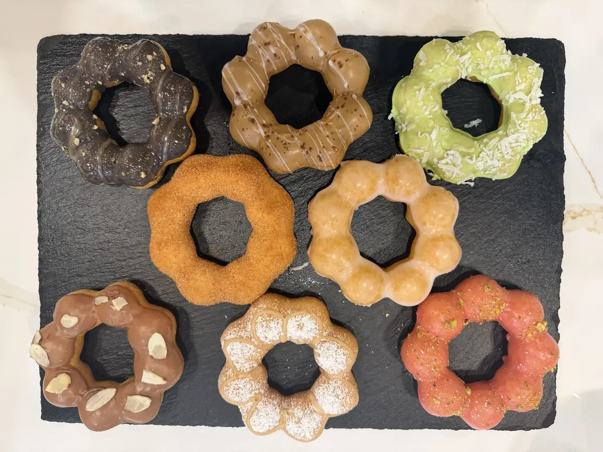 This week's lineup on a slate board: Nutella Almonds, Maple Blueberry Pie, Churro, Maple Funnel, Vietnamese Coffee, Original, Pistachio Raspberry and Coconut Melona